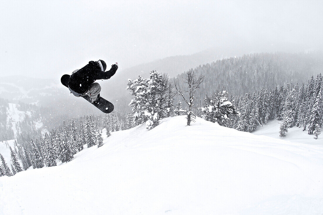 A man on a snowboard flies through the air after hitting a jump Jackson, Wyoming, USA