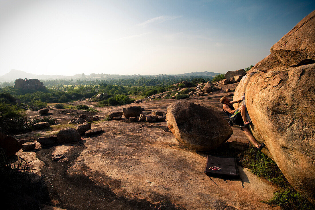 Male climber bouldering alone in vast boulderfield in Hampi, India Hampi, Karnataka, India