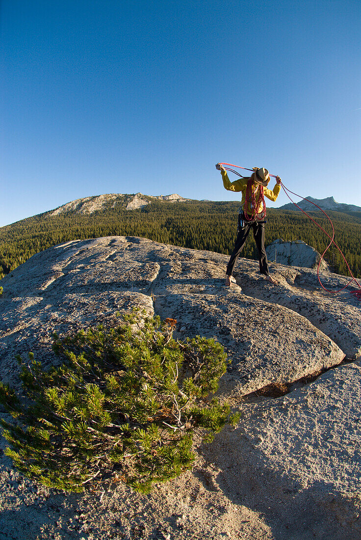 A young woman coils her climbing rope after an afternoon climb CA, USA