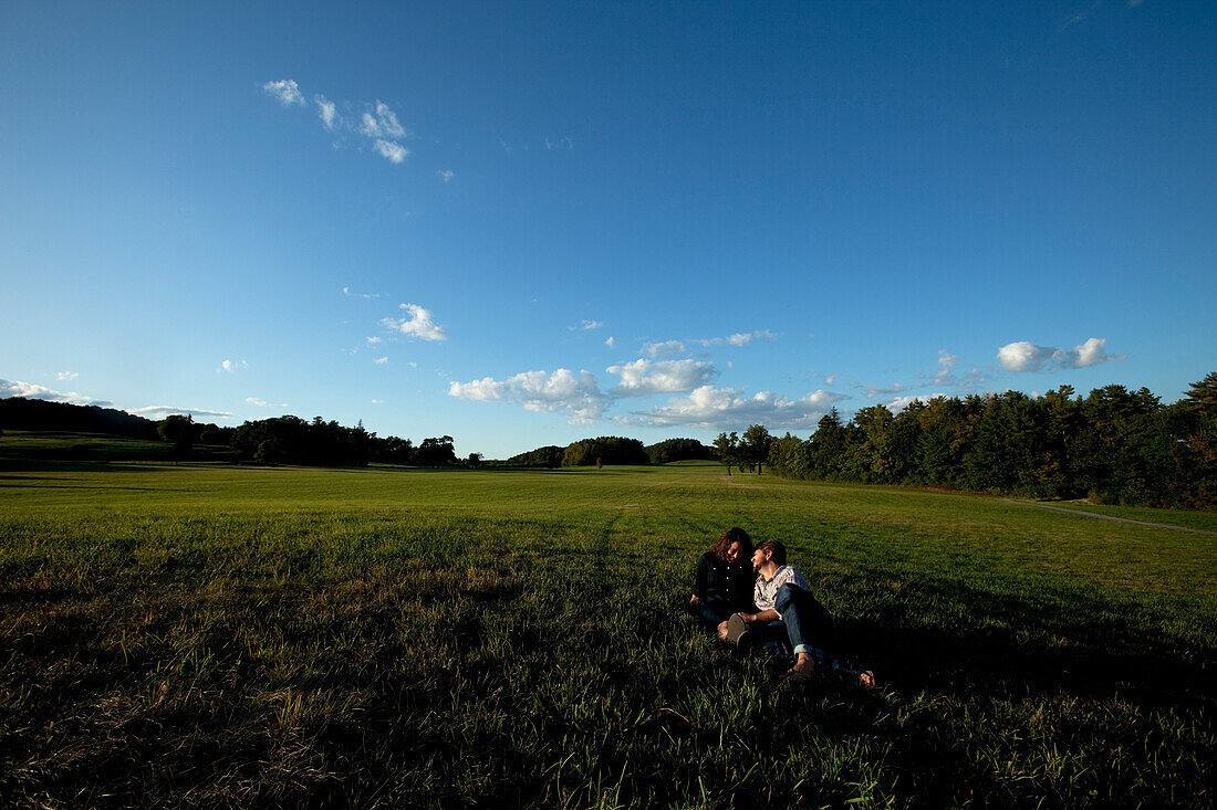 Man and woman laughing and laying in a grass field in nice light Shelburne / Burlington, Vermont, USA