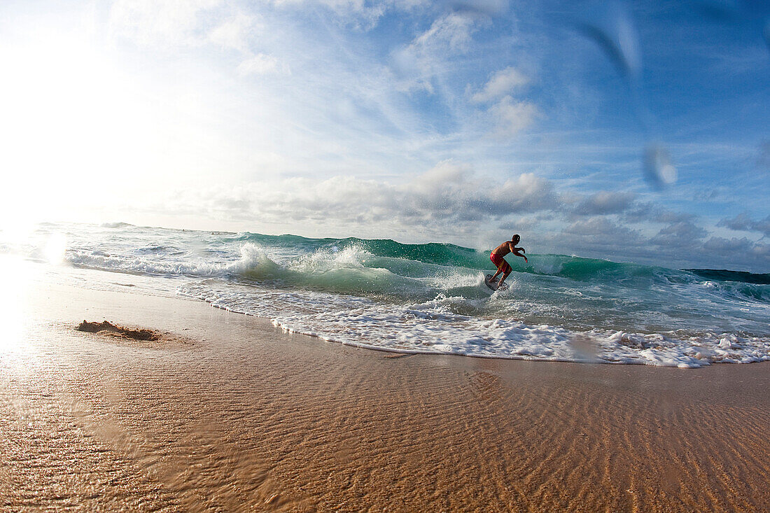 One man skimboarding into big waves in nice light Honolulu, Hawaii, USA