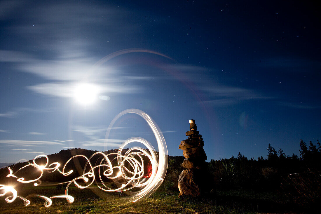 Rock cairn with light painting next to it and full moon in background in Idaho Sandpoint, Idaho, USA