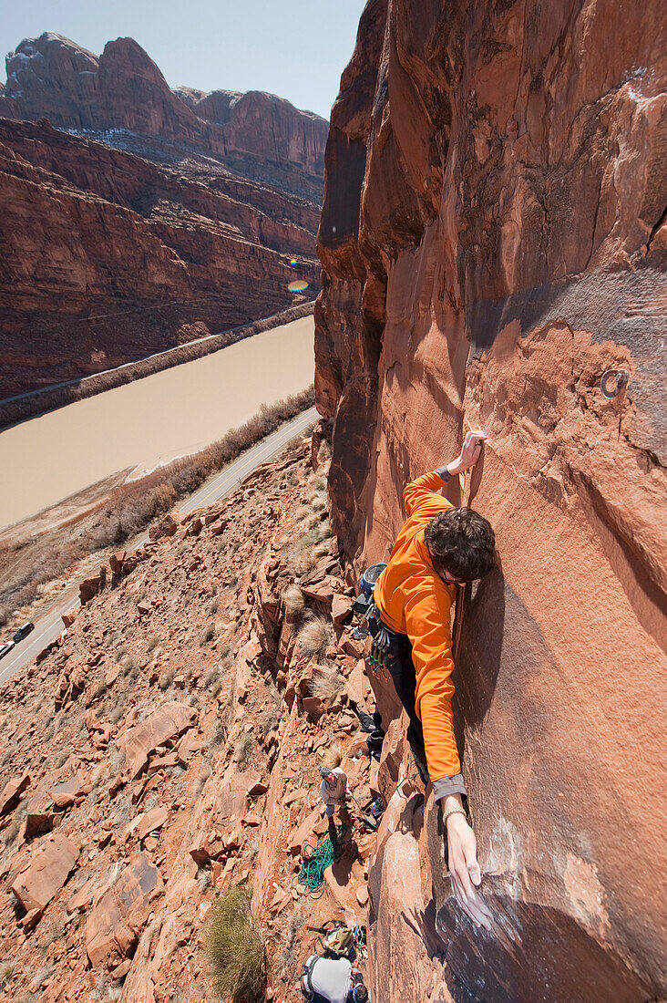 A young man rock climbs near Moab, UT Moab, Utah, USA