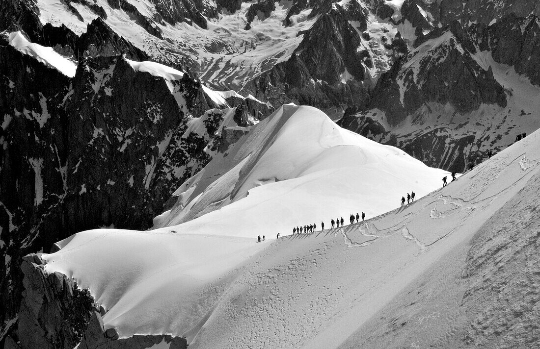 Hikers trek down a snowy ridge below Mont Blanc, France Mont Blanc, France