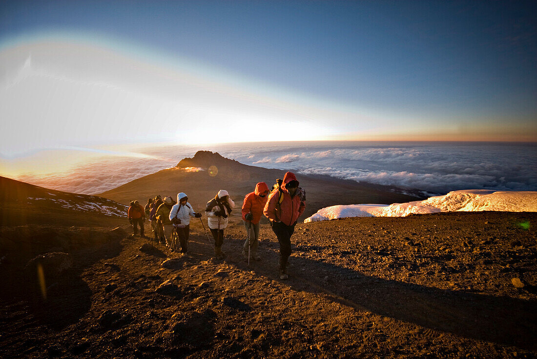 A team of hikers approach the summit of Mt. Kilimanjaro at sunrise after trekking six hours through the night Tanzania
