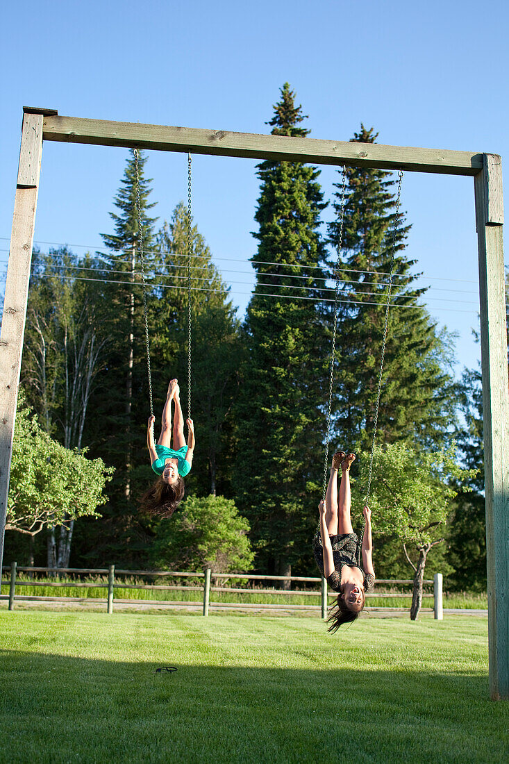 Two young women swinging smile while looking back on a summer day Sandpoint, Idaho, USA