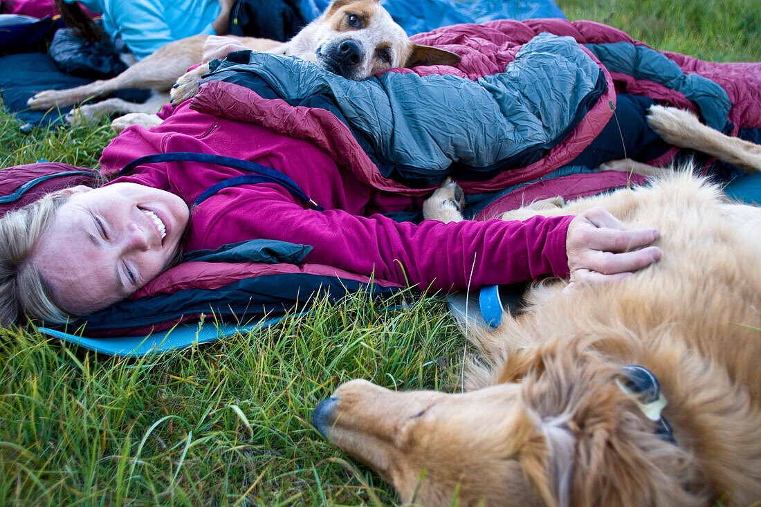 A woman curls up with her dogs during a summer sleep out Utah, USA