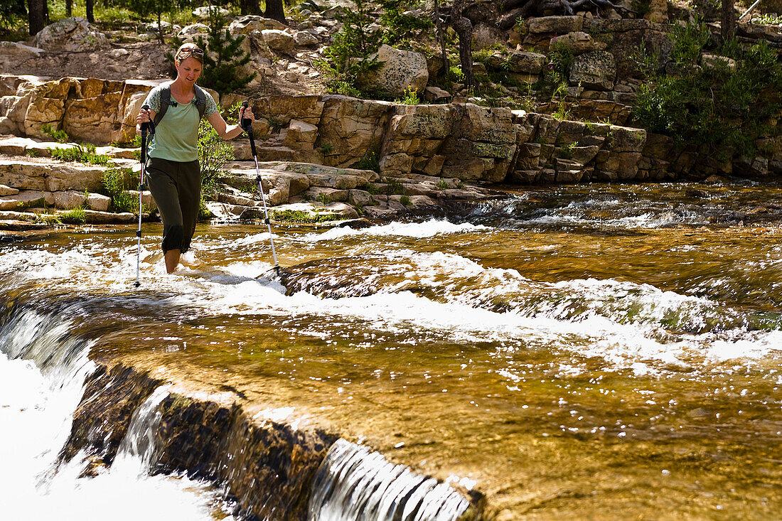 A woman wades across the Provo River in Utah's Uinta Mountains Utah, USA