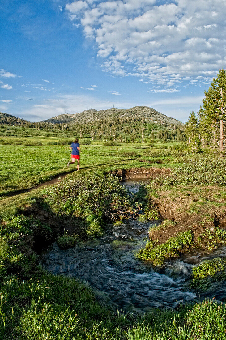 A young woman enjoys the evening light and empty trail during an evening trail run in Lake Tahoe, Nevada Incline Village, Nevada, USA