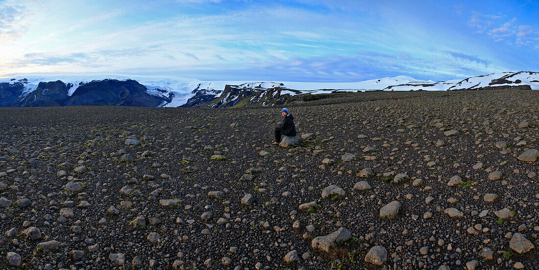 Hiker sitting in boulder field in Iceland, Iceland