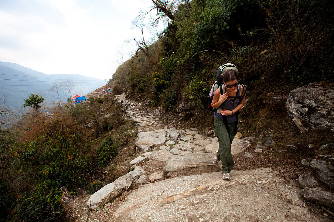 A female trekker shoulders her rucksack uphill in Nepal Annapurna Conservation Area, Nepal