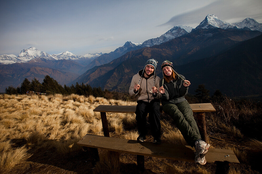 A trekking couple adjust their hats infront of the Annapurna mountain range in Nepal Annapurna Conservation Area, Nepal