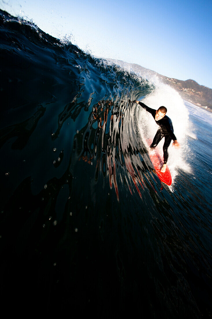 A male surfer pulls into a barrel at Zuma beach in Malibu, California Malibu, California, United States of America