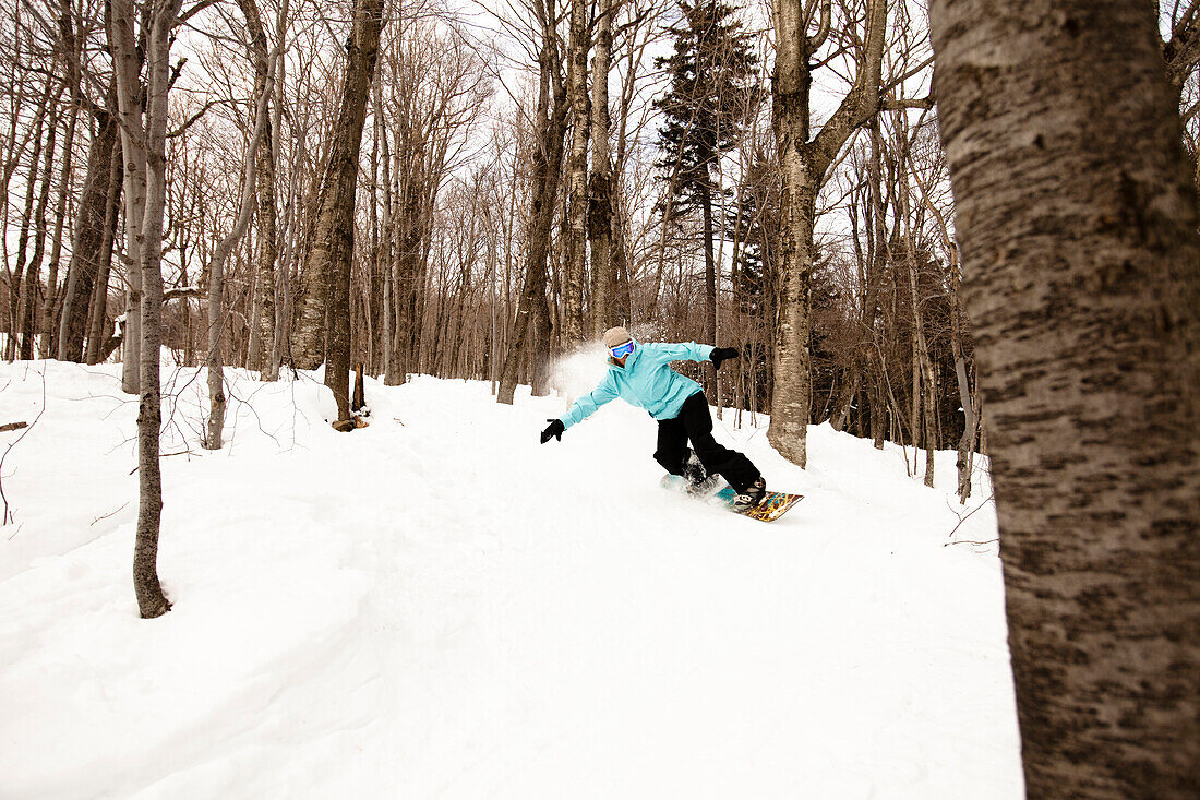 An experienced female snowboarder comes down a glade in Killington, Vermont Killington, Vermont, United States of America
