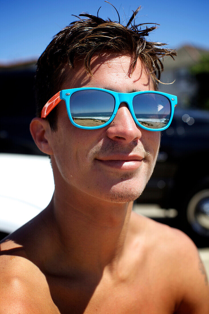 Portrait of male surfer wearing colorful sunglasses San Diego, CA, USA