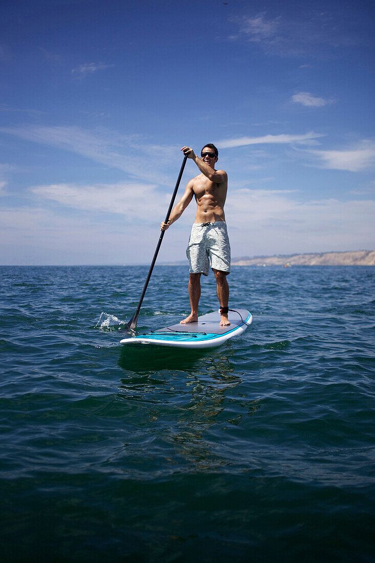 Male stand up paddling in the ocean San Diego, CA, USA