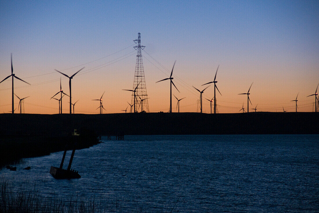 Wind turbines and power transmission lines at sunset near San Francisco, CA, usa