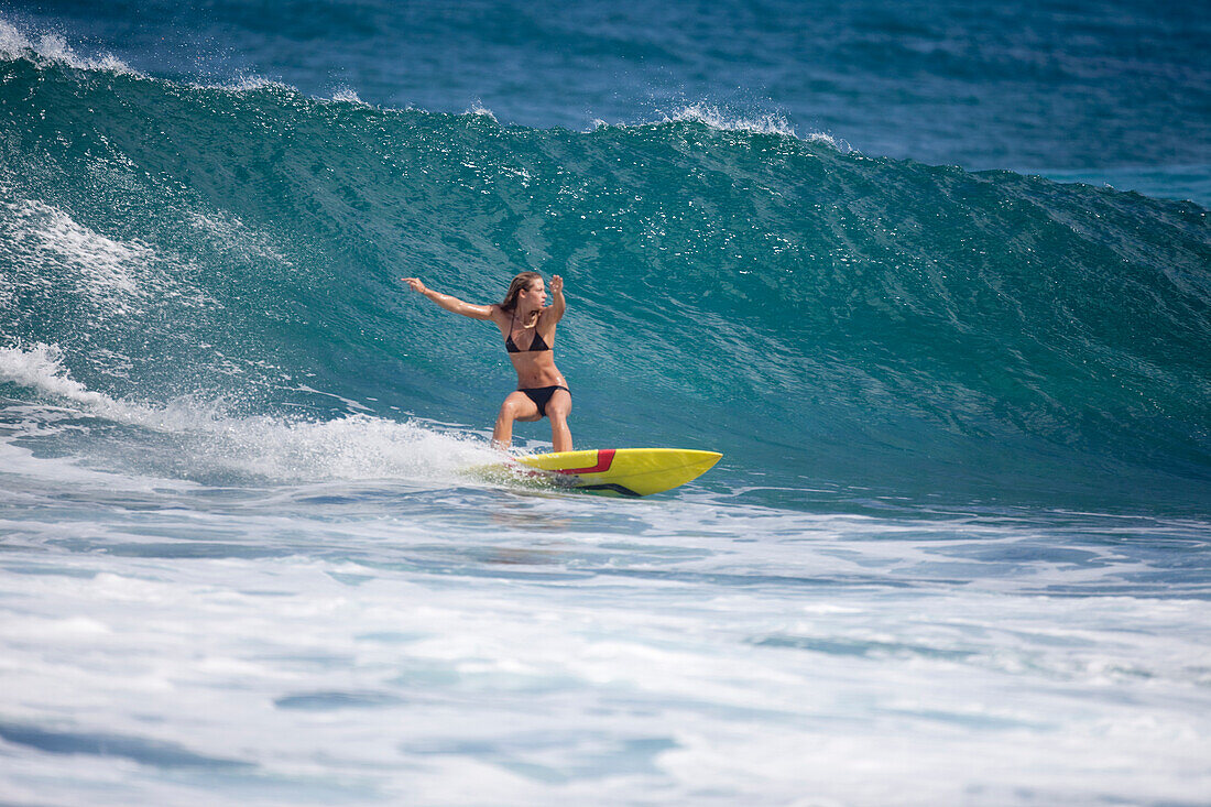 A surfer girl surfing at Rocky Point, on the north shore of Oahu, Hawaii North Shore, Oahu, Hawaii, USA