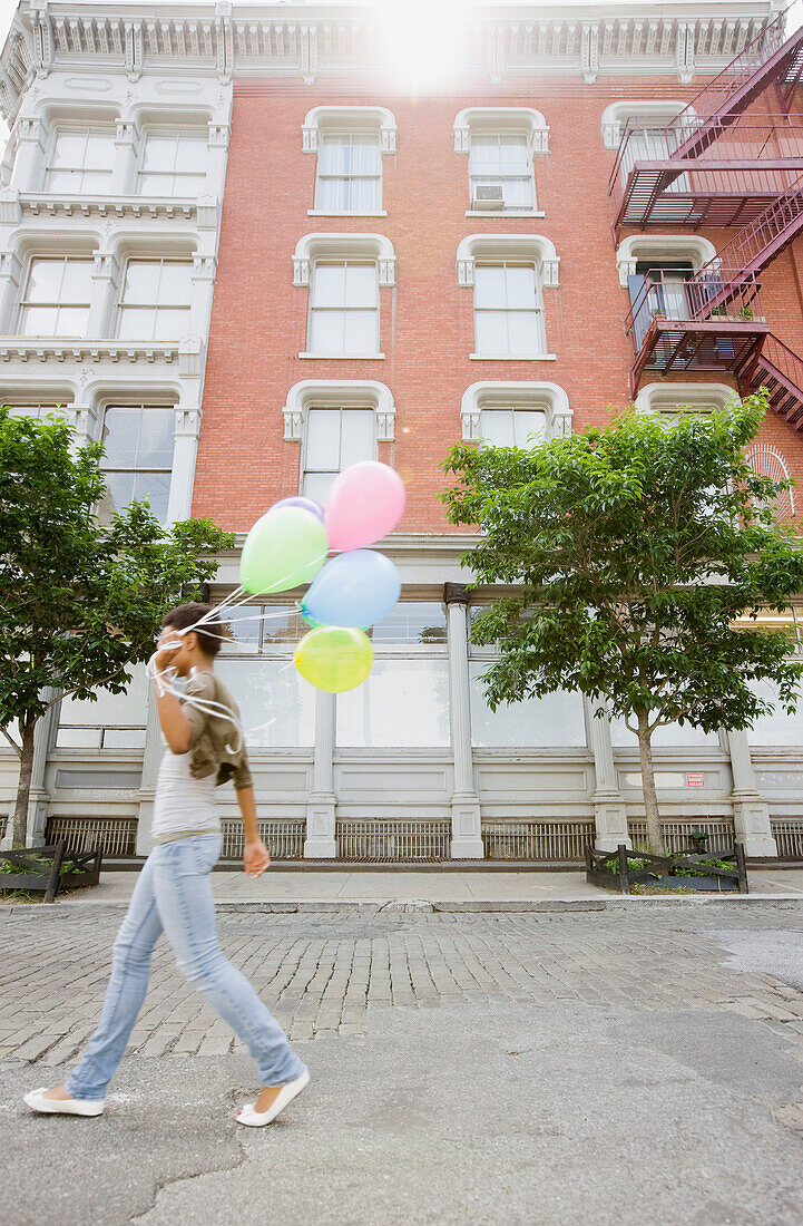 African woman walking with bunch of balloons, Jersey City, NJ