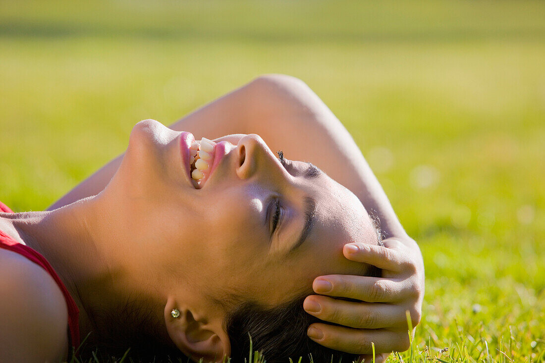 Hispanic woman laying in grass smiling, Seattle, WA