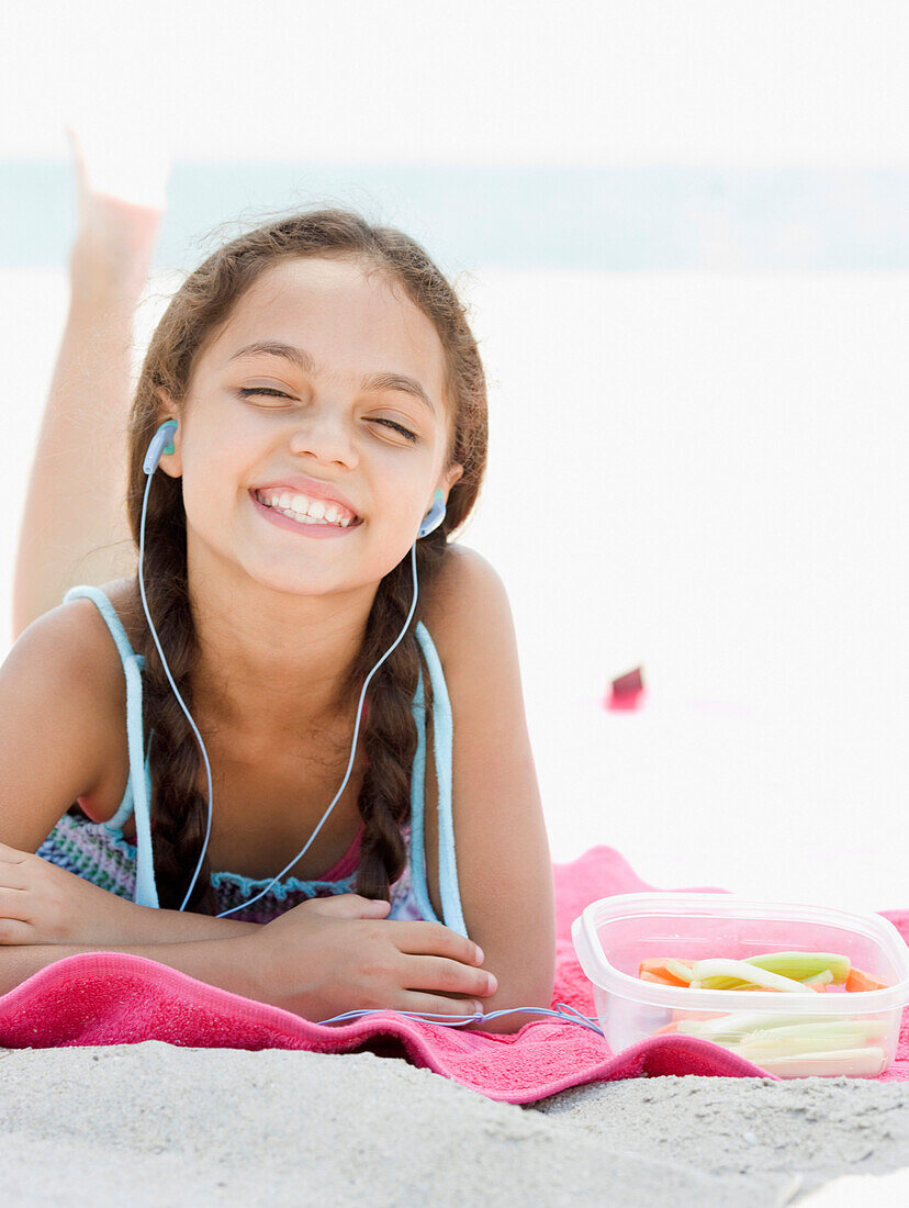 Hispanic girl listening to mp3 player on beach, Rockaway Beach, NY