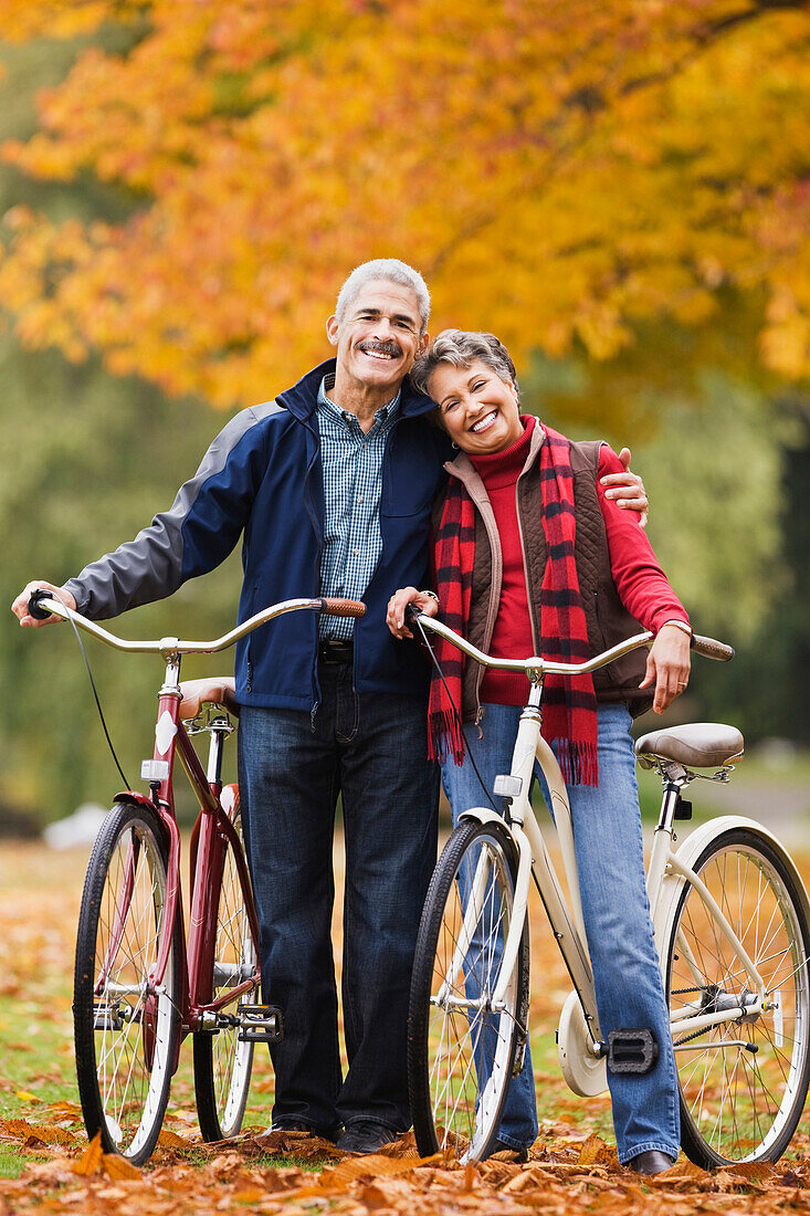 African couple standing with bicycles in park in autumn, Seattle, WA