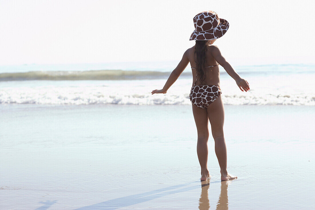 Young mixed race girl standing at beach, Venice Beach, CA