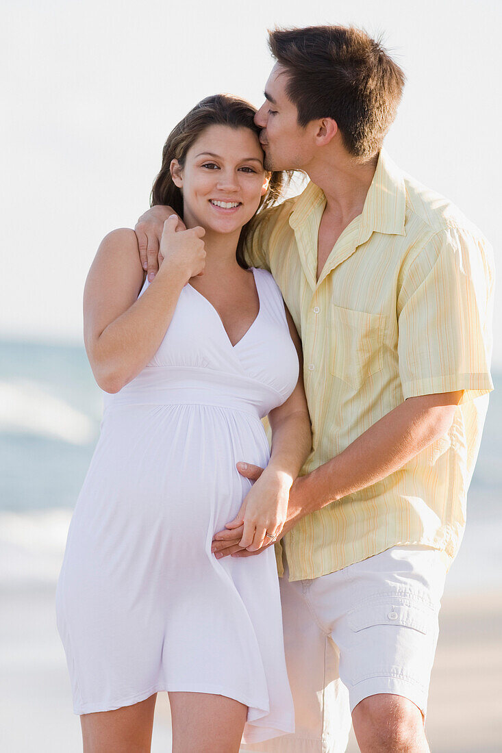 Husband hugging pregnant wife on beach, Fort Lauderdale, FL