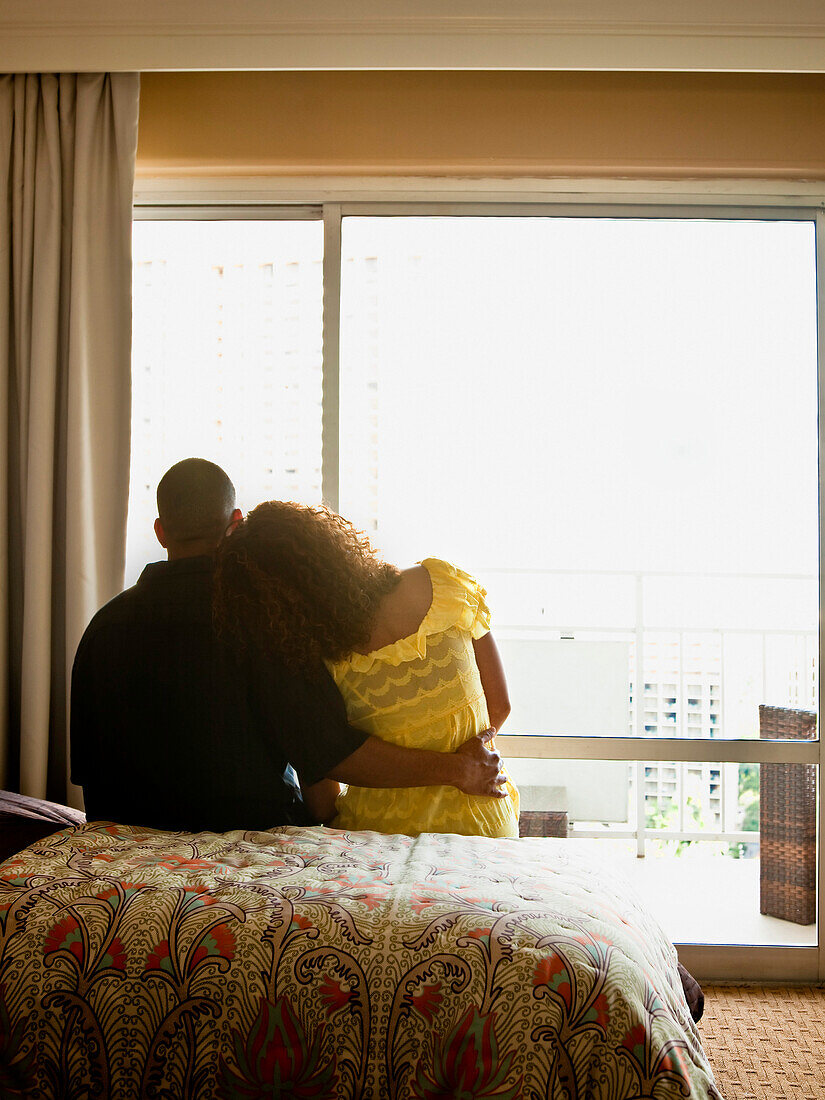 Couple hugging on bed, Honolulu, HI