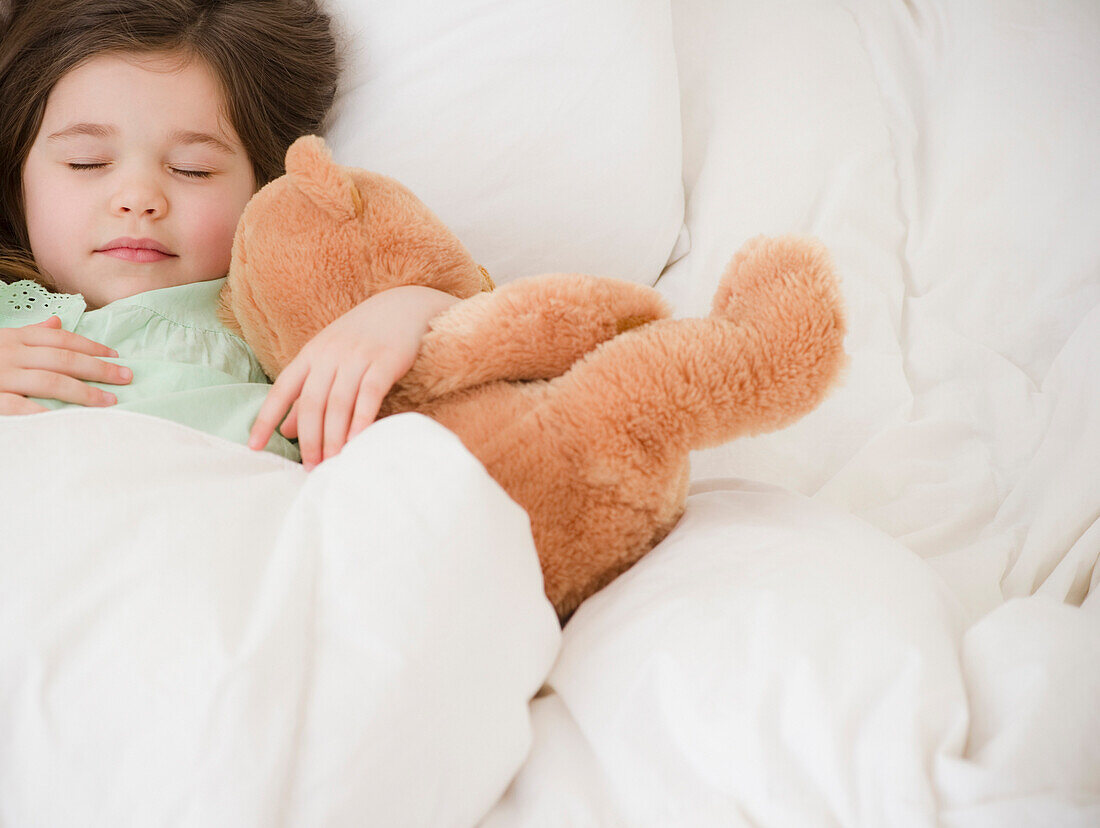 Mixed race girl sleeping with teddy bear, Jersey City, New Jersey, United States