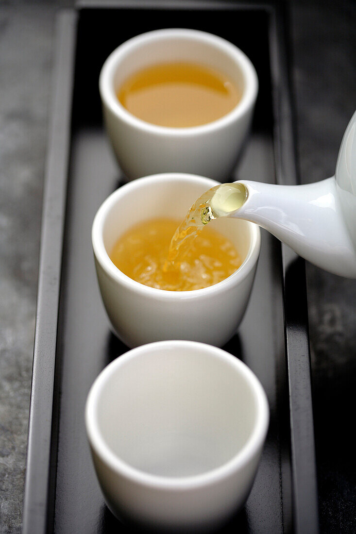 Green tea being poured from teapot into cups on tray, Santa Fe, New Mexico, United States