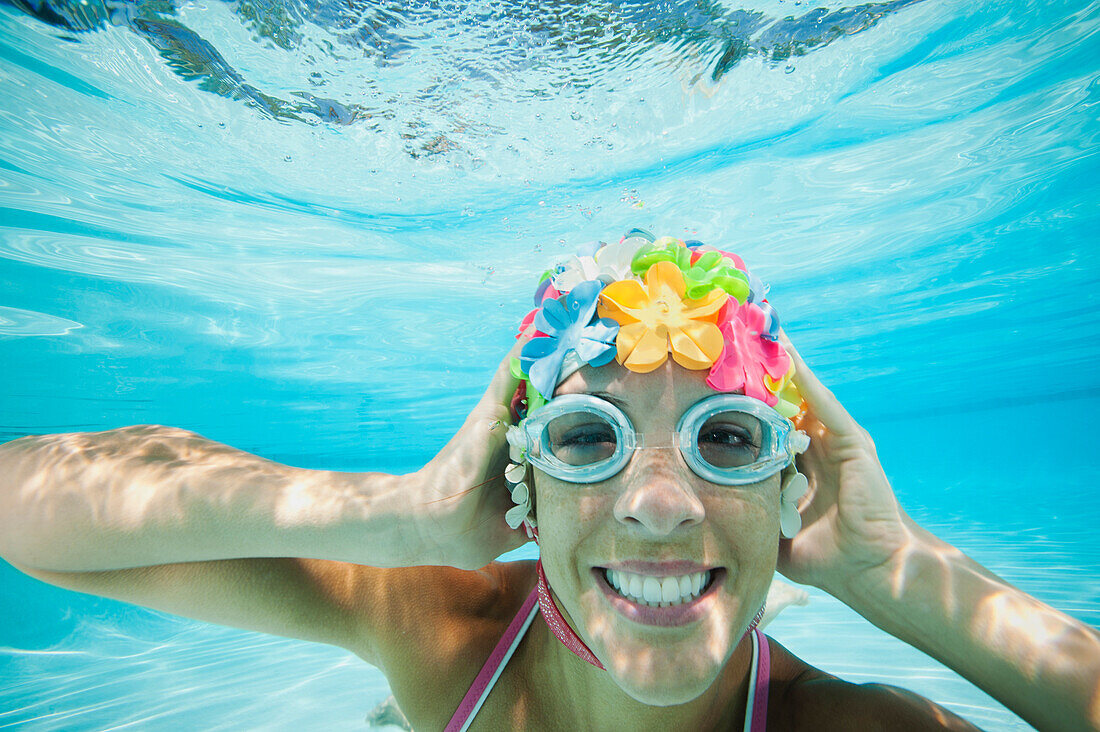 Hispanische Frau mit Retro-Schwimmkappe unter Wasser im Schwimmbad, Ladera Ranch, CA, USA