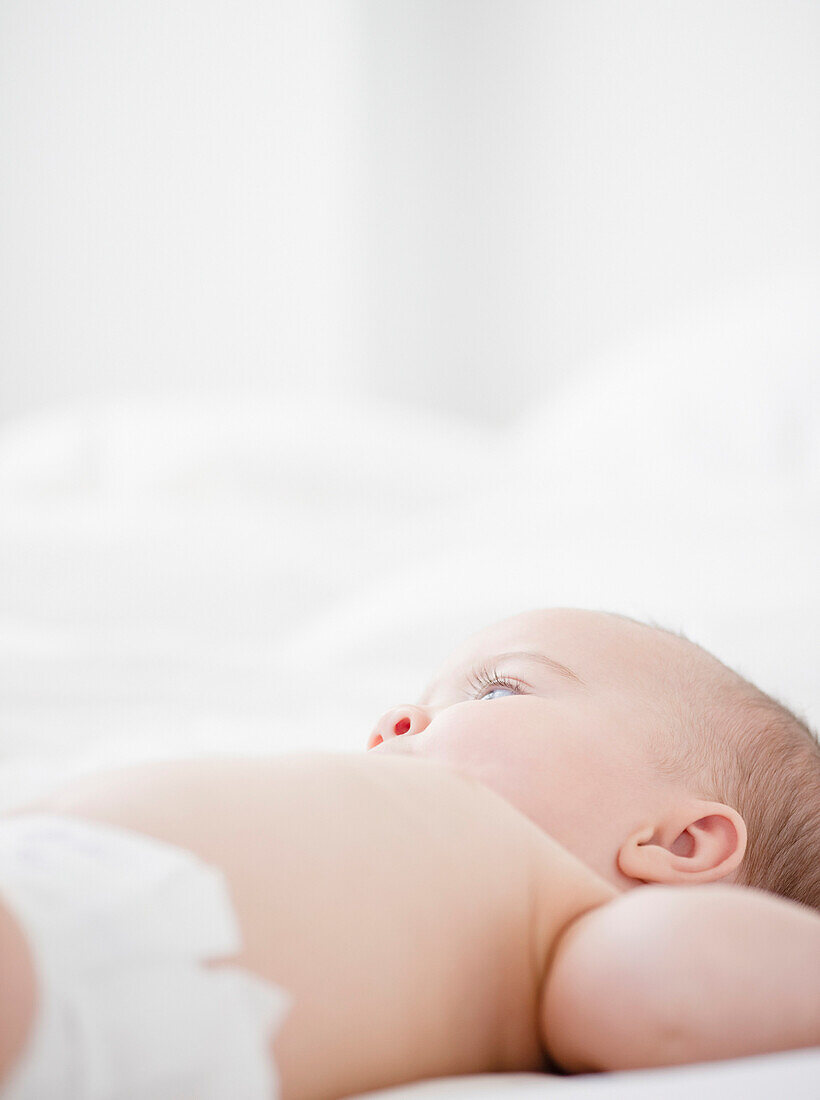 Mixed race baby laying on bed, Jersey City, New Jersey, USA