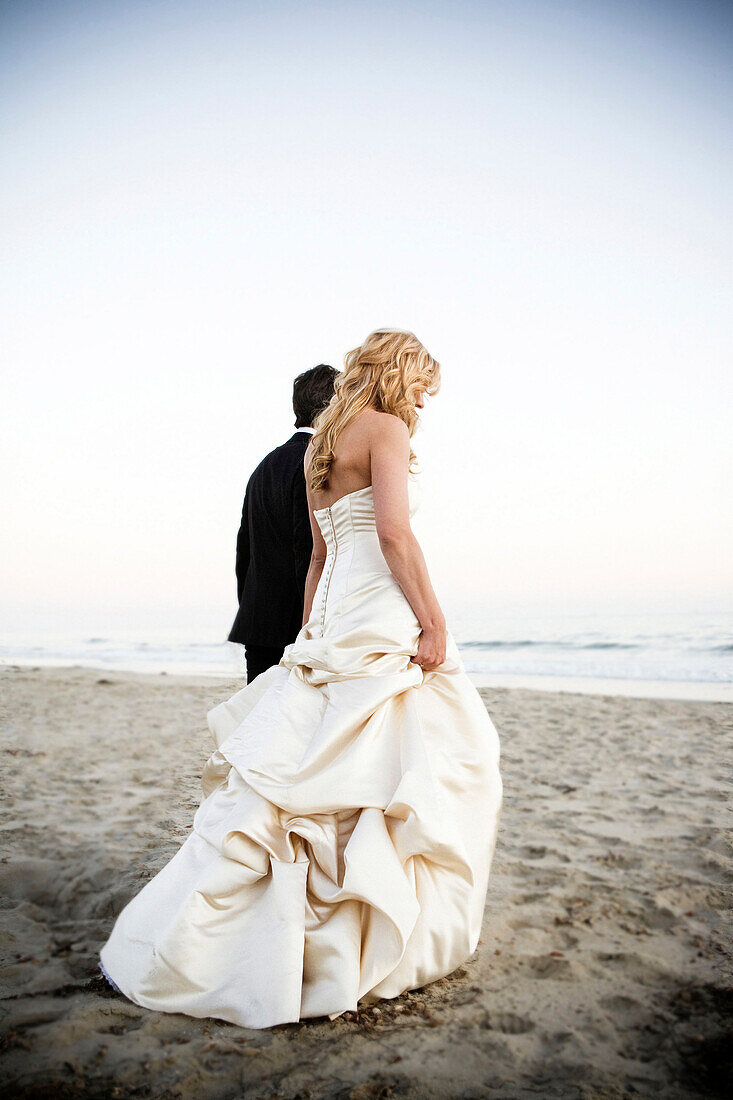 Bride and groom walking on beach, Santa Barbara, California, USA