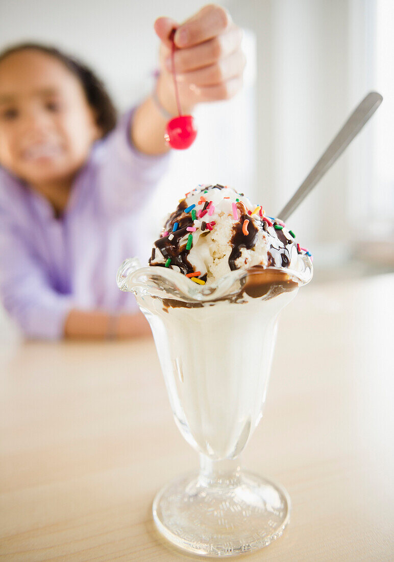 African American girl putting cherry ice cream sundae, Jersey City, New Jersey, USA