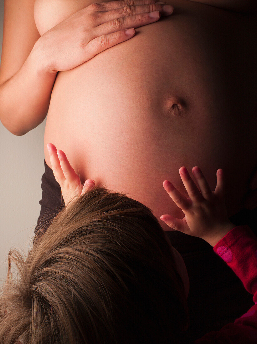 Child patting pregnant mother's stomach, New York, New York, United States