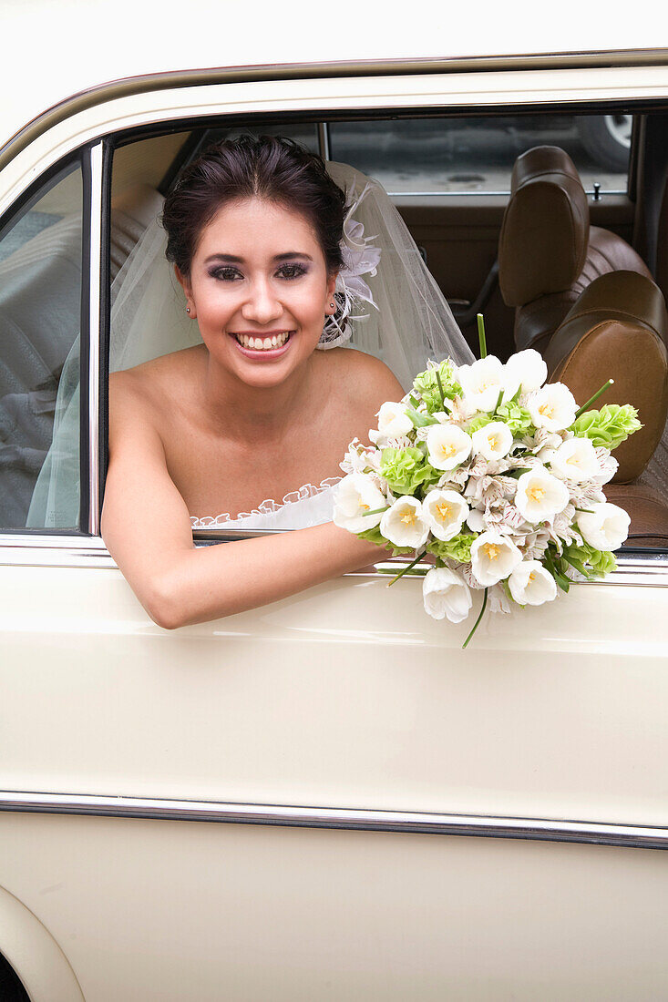 Hispanic bride sitting with bouquet in back of car, Zacatecas, Zacatecas, Mexico