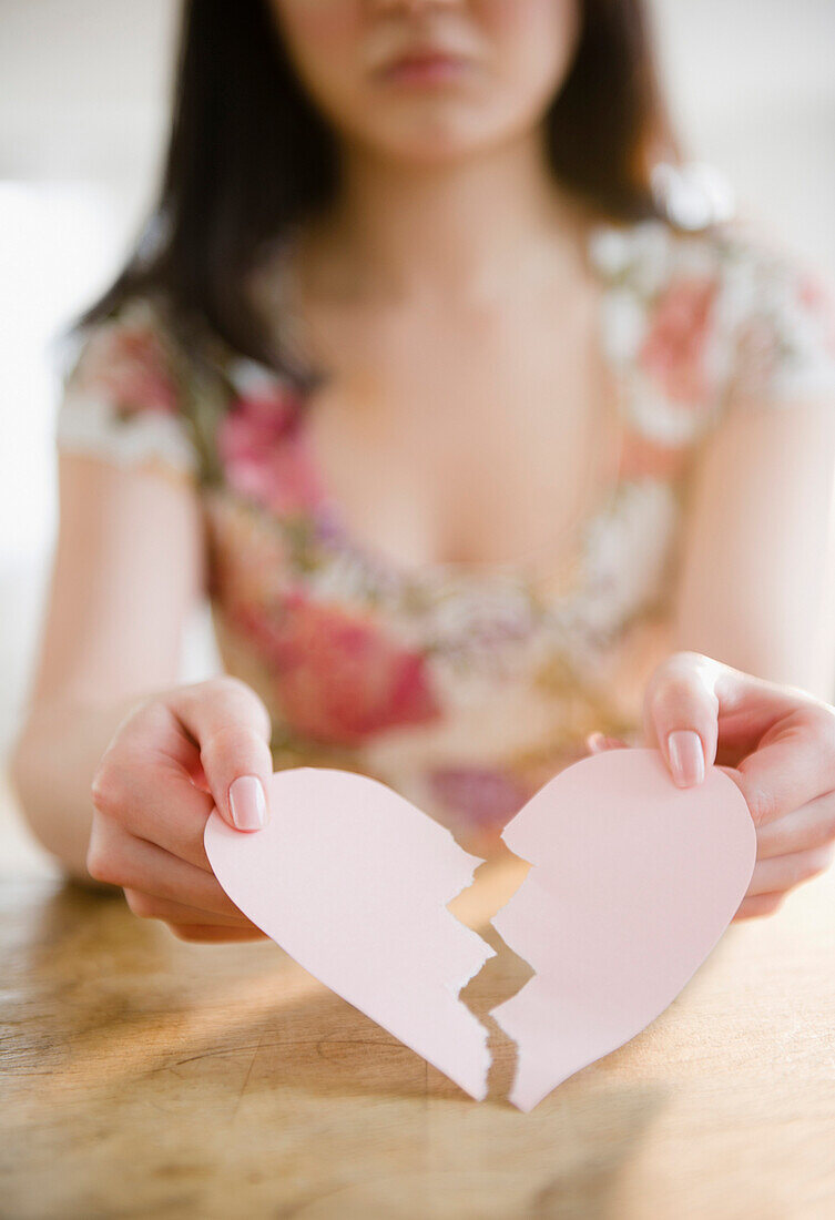 Korean woman holding torn paper heart, Jersey City, New Jersey, USA
