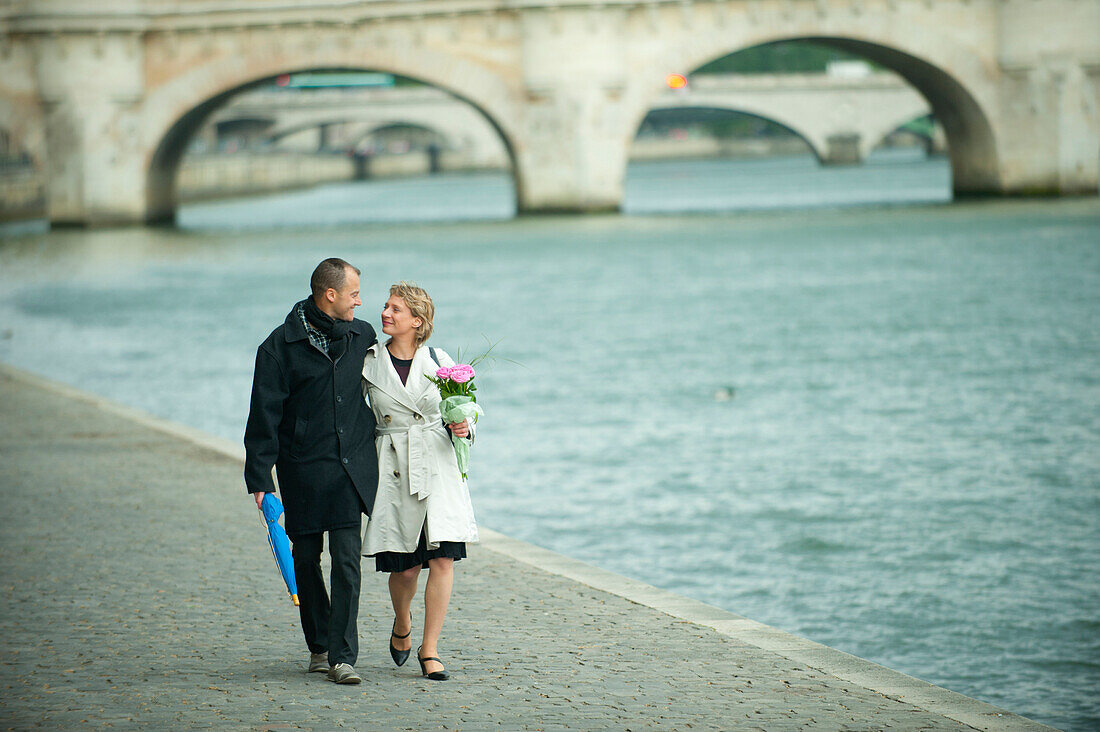 Caucasian couple walking near city river, Paris, Paris, France