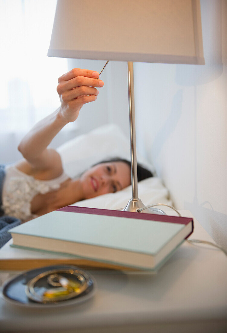 Brazilian woman turning of lamp in bedroom, Jersey City, New Jersey, United States