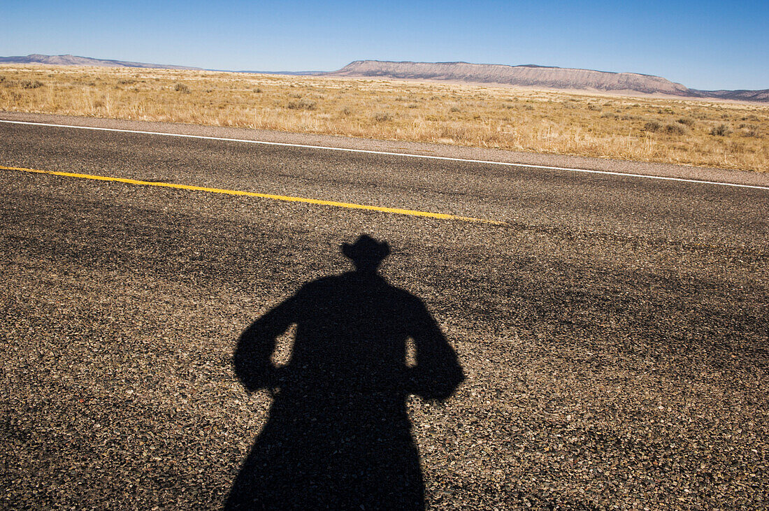Shadow of cowboy on remote highway, Page, Arizona, United States