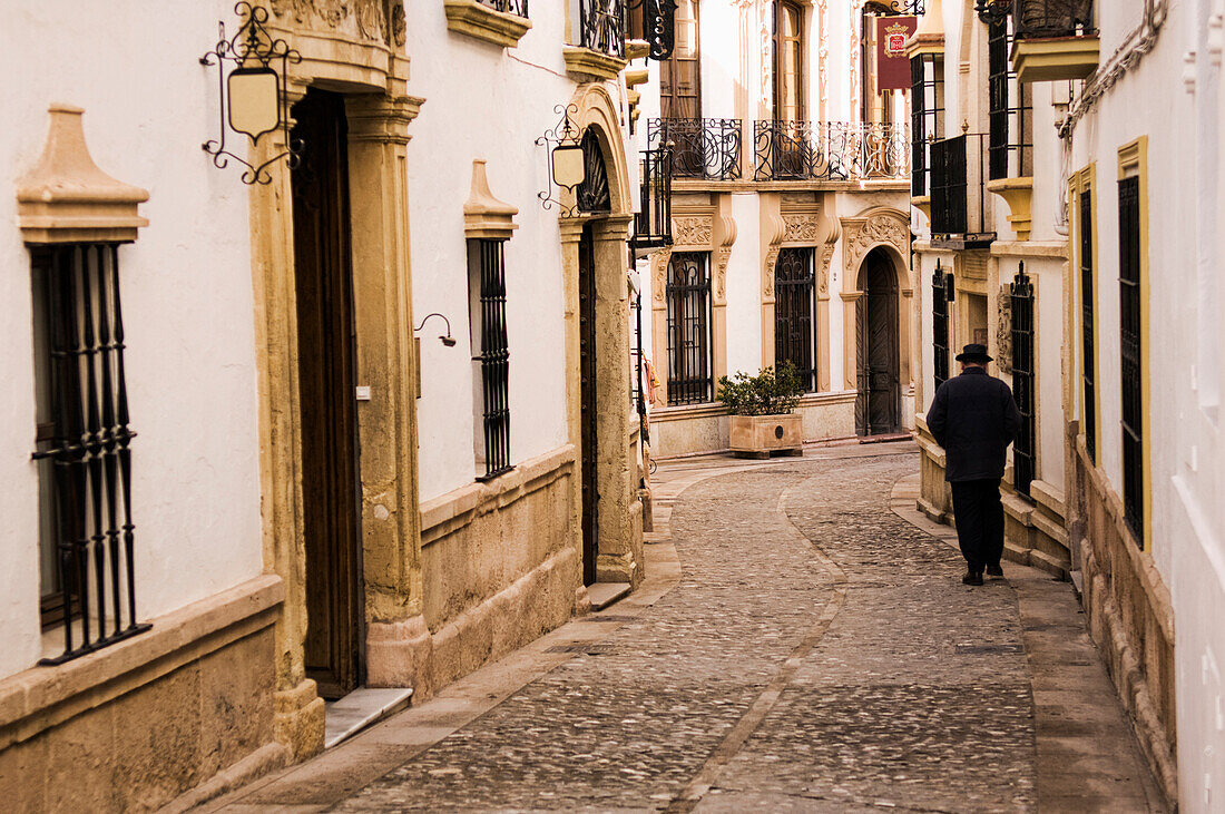 Man walking down cobblestone alley in quaint village, Carmona, Andalucia, Spain