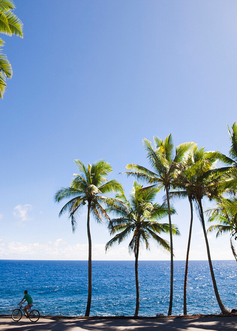 Caucasian woman bike riding near tropical ocean, Pahoa, Hawaii, United States