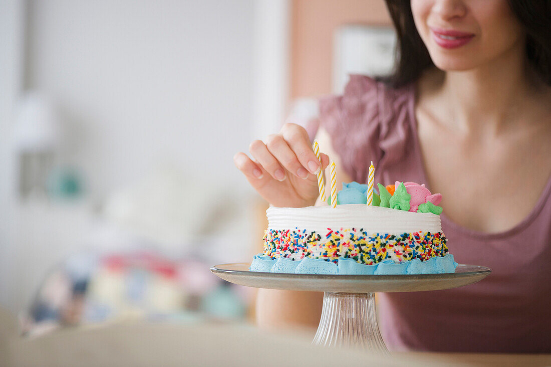 Mixed race woman preparing birthday cake, Jersey City, New Jersey, USA
