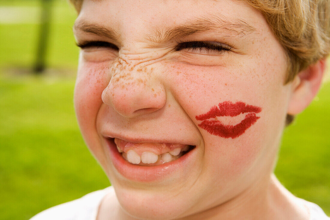 Grimacing boy with lipstick kiss on face, Elk Grove, CA, USA