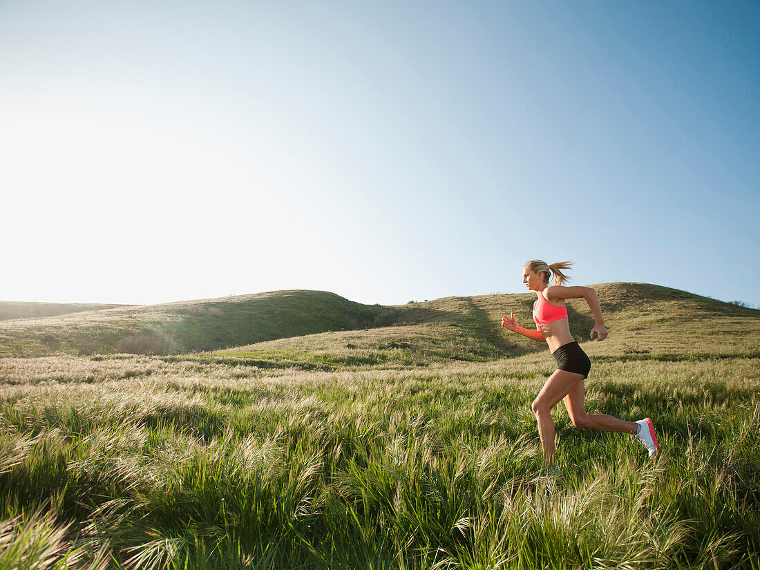 Caucasian woman running in remote field, Ladera Ranch, California, USA