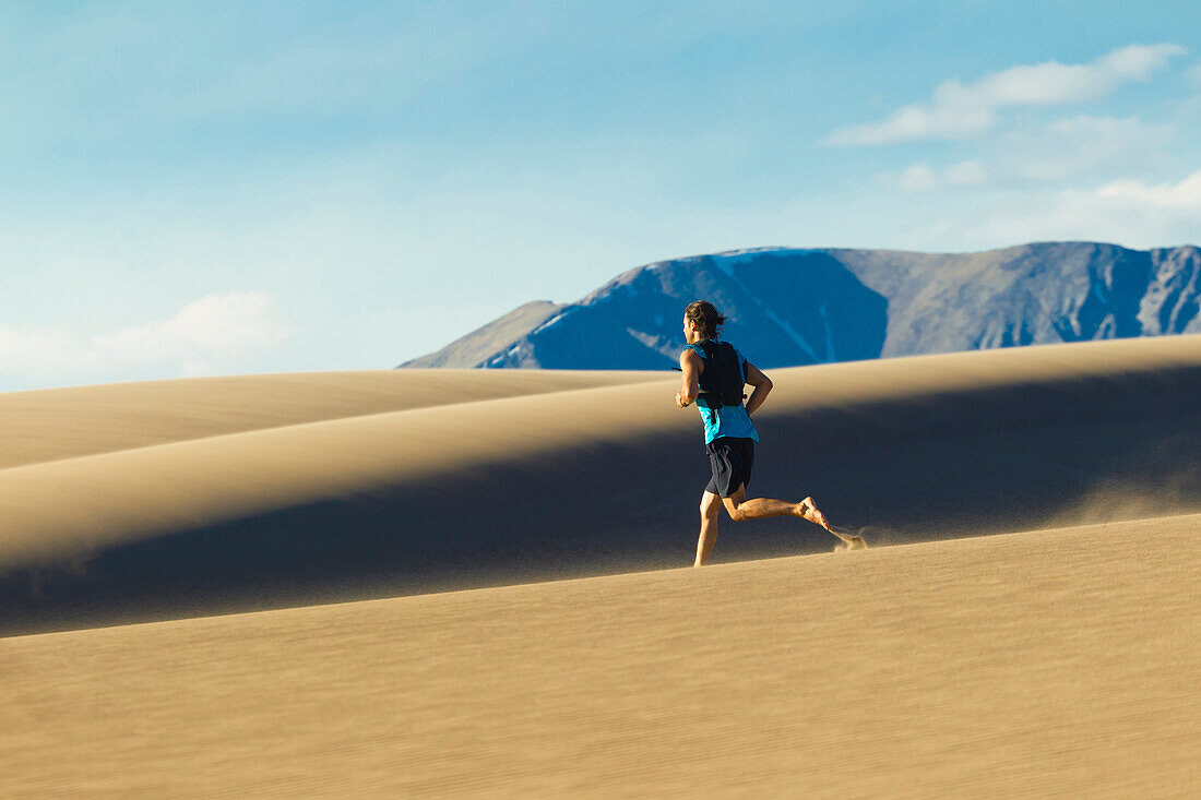 Hispanic man running on sand dune, Great Sand Dunes National Park, Colorado, USA