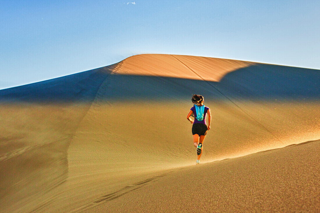Hispanic woman running on sand dune, Great Sand Dunes National Park, Colorado, USA