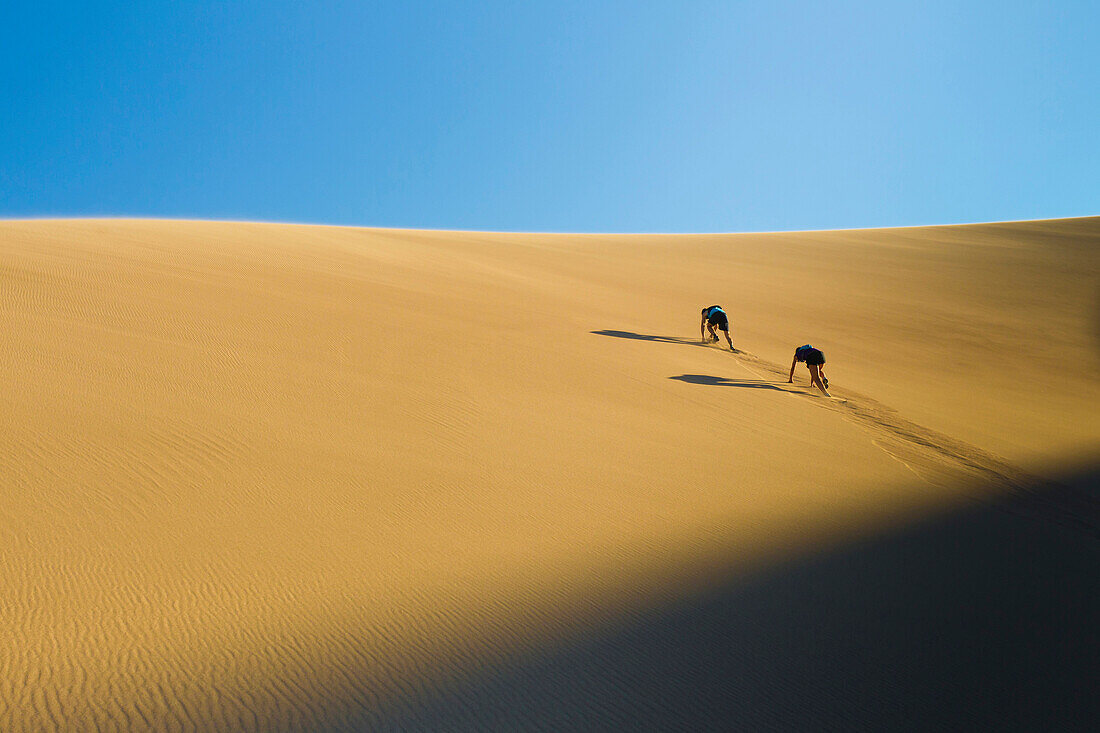 Hispanic couple climbing sand dune, Great Sand Dunes National Park, Colorado, USA