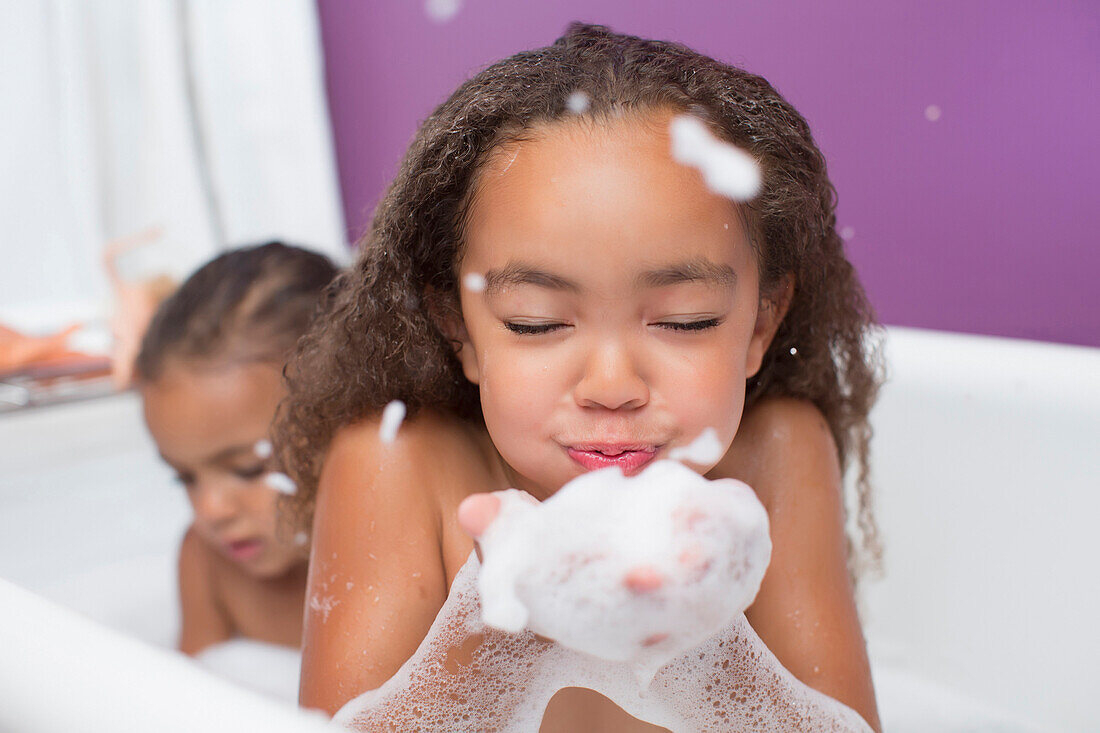 Gemischtrassige Mädchen spielen mit Seifenblasen in der Badewanne, Portland, OR, USA